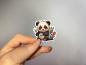 Preview: Hand, die einen Aufkleber in Form eines niedlichen Pandas mit Bambus und Blumen hält, gestaltet von DreamArt VM.