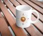 Preview: Weißer Keramikbecher mit einem leuchtenden Boho-Sonnenmotiv, umgeben von Pfeilen, Federn und dekorativen Details. Der Becher steht auf einem Holztisch und ist perfekt für Liebhaber spiritueller Symbole und boho-inspirierter Kunst.