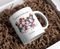 Preview: Personalisierte Weihnachtstasse mit einer lächelnden Schneemannfamilie, die warme Winterkleidung trägt. Oben steht der Text 'Fröhliche Weihnachten', und darunter kann ein Name wie 'Natalia' hinzugefügt werden. Die Tasse ist perfekt für persönliche Weihnac