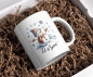 Preview: Weihnachtstasse mit fröhlichem Schneemann und dem Schriftzug 'Let it Snow'. Der Schneemann trägt eine winterliche Mütze und Schal und ist von Schneeflocken umgeben. Perfekt für warme Getränke zur Weihnachtszeit.