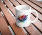 Preview: Weiße Keramik-Tasse mit farbenfrohem Musiknoten-Design, auf einem Holztisch im Freien präsentiert. Perfekt für Musikliebhaber und ideal für Kaffee- oder Teepausen.