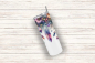 Preview: Einzelner Tumbler mit detailreichen Blumen-, Kristall- und Federdesigns in lebendigen Farben auf weißem Hintergrund, liegend auf einer rustikalen Holzoberfläche. Perfekt für naturinspirierte Trinkliebhaber.