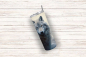 Preview: Ein einzelner Thermobecher mit einem eindrucksvollen Wolfsmotiv, das das Gesicht eines grauen Wolfs mit aufmerksamem Blick zeigt. Der Becher hat einen silbernen Deckel und Edelstahlstrohhalm und ist auf einem hellen Holz-Hintergrund positioniert.