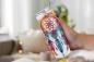 Preview: Hand hält einen Thermobecher mit detailreichem Traumfänger-Design, verziert mit bunten Federn und floralen Elementen im Boho-Stil. Das Bild vermittelt eine gemütliche Atmosphäre, perfekt für Liebhaber von Boho-Accessoires.