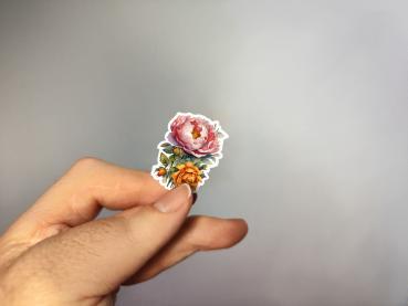 Preview: Blumen Sticker Sheet – Strahlende Blütenpracht für kreative Projekte Preview: Kleiner Sticker mit handgezeichneten Blumen in rosa und orange, gehalten in der Hand.