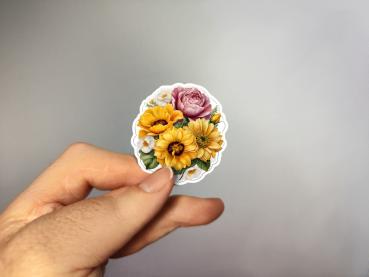 Hand, die einen Blumenaufkleber mit gelben, weißen und rosa Blüten hält, gestaltet von DreamArt VM.