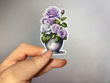 Aufkleber einer Blumenvase mit lila und weißen Rosen, umgeben von grünen Blättern. Ideal zur Dekoration und für kreative Projekte.
