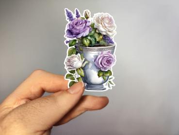 Aufkleber einer eleganten Blumenvase mit lila, weißen und rosa Rosen sowie Lavendel, umgeben von grünen Blättern. Perfekt für kreative Projekte und Dekoration.