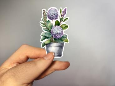 Aufkleber einer Pflanze mit lila Blüten in einem silbernen Topf, umgeben von grünen Blättern. Perfekt für dekorative Anwendungen und kreative Projekte.