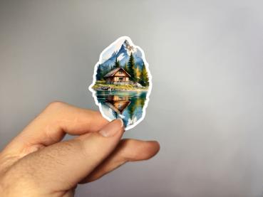 Einzigartiger Sticker mit Berghütte und See, handgefertigt und in der Hand präsentiert