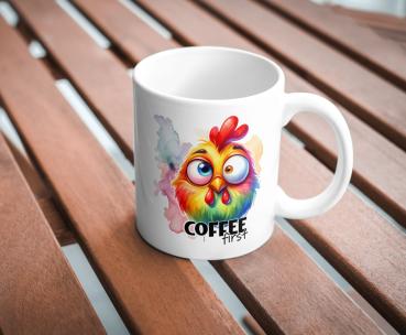 Weißer Kaffeebecher mit buntem, lustigem Hühnerdesign und dem Text 'Coffee first' auf einer Holzoberfläche. Perfekt für humorvolle Kaffeeliebhaber.