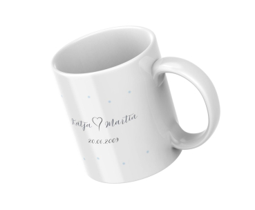 Weiße Keramiktasse mit Namen Katja und Martin und Datum 20.06.2009, schräg liegend dargestellt.