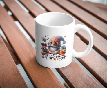 Weißer Kaffeebecher mit niedlichem Gnom-Design, umgeben von bunten Blumen und Bastelutensilien, auf einer Holzoberfläche. Perfektes Geschenk für kreative Seelen und Gartenliebhaber.
