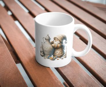 Weißer Kaffeebecher mit niedlichem Gnom-Design, der eine kunstvoll verzierte Kanne bemalt, umgeben von Farbpaletten, auf einer Holzoberfläche. Ideal für kreative Seelen und Kunstliebhaber.
