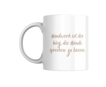 Weiße Tasse mit einem handgeschriebenen Spruch in beiger Farbe: ‚Handwerk ist der Weg, die Hände sprechen zu lassen.‘ Ein minimalistisches Design, das die Bedeutung des Handwerks und der Handarbeit hervorhebt.