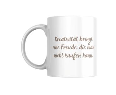 Ein weißer Keramikbecher mit dem Zitat 'Kreativität bringt eine Freude, die man nicht kaufen kann' in eleganter Schriftart. Der Becher steht auf einem neutralen Hintergrund.