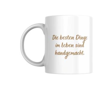 Weißer Keramikbecher mit der Aufschrift ‚Die besten Dinge im Leben sind handgemacht‘ in einer stilvollen, geschwungenen Schrift. Ein ideales Geschenk für alle, die handgefertigte Produkte und Kreativität schätzen.