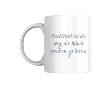 Weißer Keramikbecher mit der Aufschrift ‚Kreativität ist der Weg, die Hände sprechen zu lassen‘ in einer eleganten, geschwungenen Schrift. Perfektes Geschenk für kreative Köpfe und Handarbeitsliebhaber.