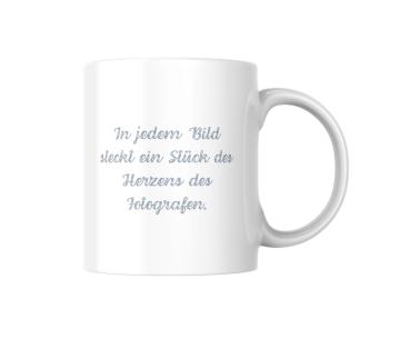 Weißer Keramikbecher mit einem Zitat in hellblauer, handgeschriebener Schrift: ‚In jedem Bild steckt ein Stück des Herzens des Fotografen.‘ Der Becher hat ein minimalistisches Design, das die Bedeutung des Zitats hervorhebt.