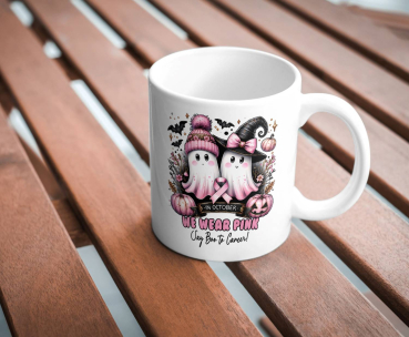 Preview: Halloween-Tasse „We Wear Pink – Say Boo to Cancer“ – Unterstützen Sie den Kampf gegen Brustkrebs Preview: Weiße Tasse mit Halloween-Design: zwei Geister mit rosa Schleife für den Kampf gegen Brustkrebs, einer mit rosa Mütze, der andere mit Hexenhut. Umgeben von Kürbissen, Fledermäusen und dem Text ‚We Wear Pink – Say Boo to Cancer‘. Auf einem Holztisch platzi