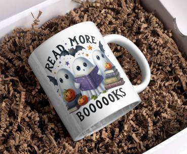 Weiße Tasse mit Halloween-Motiv von drei süßen Geistern, die ein Buch lesen, umgeben von Kürbissen und einem Fledermaus-Design, mit dem Text ‚Read More Boooooks‘. Perfekt für Halloween- und Bücherliebhaber.