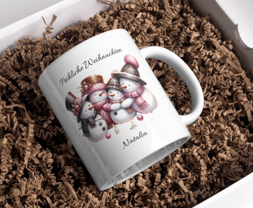 Preview: Personalisierte Tassen Fröhliche Weihnachten Preview: Personalisierte Weihnachtstasse mit einer lächelnden Schneemannfamilie, die warme Winterkleidung trägt. Oben steht der Text 'Fröhliche Weihnachten', und darunter kann ein Name wie 'Natalia' hinzugefügt werden. Die Tasse ist perfekt für persönliche Weihnac