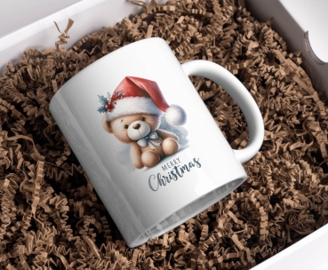 Weihnachtstasse mit niedlichem Teddybär in einer Weihnachtsmütze und dem Text 'Merry Christmas'. Der Teddybär trägt eine Schleife und ist von weihnachtlichen Details wie Stechpalmenzweigen umgeben. Perfekte Tasse für festliche Weihnachtsstimmung.