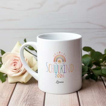 Preview: Personalisierte Tasse „Schulkind 2026“ – Motiv A mit kleinem Regenbogen, Sonne und buntem Schriftzug, Name „Leona“, auf Holztisch mit Rosen im Hintergrund fotografiert.