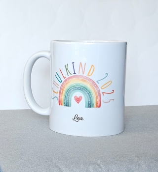 Preview: Personalisierte Tasse für Schulanfang 2025 – 4 Designs | Geschenk für Erstklässler Preview: Weiße Keramiktasse mit pastellfarbenem Regenbogen, Herzchen und dem Schriftzug „Schulkind 2025“ in Hellblau, fotografiert auf einem Holztisch.