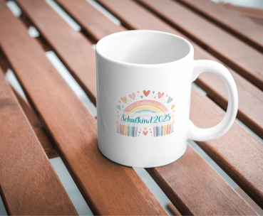 Weiße Keramiktasse  „Schulkind 2025“, fotografiert auf einem Holztisch.