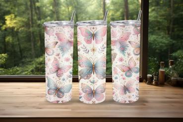 Drei Thermobecher mit pastellfarbenem Schmetterlingsdesign stehen auf einer Holzoberfläche vor einem Fenster mit grünem Waldhintergrund. Das Design zeigt rosa und blaue Schmetterlinge mit zarten Verzierungen und floralen Elementen, die eine fröhliche und