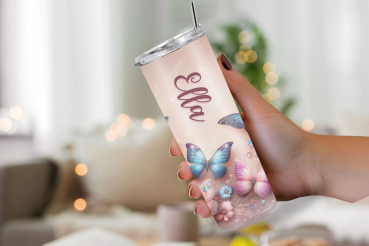 Eine Hand hält einen personalisierten Thermobecher mit dem Namen „Ella“, gestaltet mit einem märchenhaften Schmetterlings- und Blumenmotiv auf einem pastellfarbenen Hintergrund. Der Hintergrund ist weich fokussiert und erzeugt eine gemütliche, traumhafte