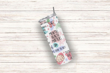 Schräg liegender weißer Thermobecher mit der Aufschrift 'Mental Health Matters' und weiteren positiven Botschaften wie 'It's okay to rest' und 'Thoughts are valid'. Der Becher ist verziert mit beruhigenden Illustrationen von Schmetterlingen, Pflanzen und