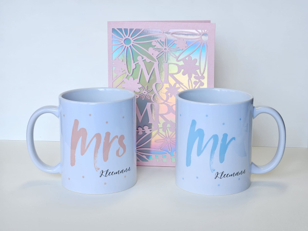 Hochzeitskarte Mr & Mrs mit personalisierten Tassen im Hintergrund