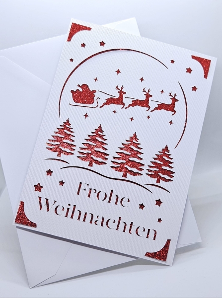 Detailaufnahme einer handgefertigten Weihnachtskarte in Weiß mit rotem Glitzerhintergrund. Filigranes Motiv zeigt Weihnachtsbäume, Sterne und den Schlitten des Weihnachtsmanns. Karte inklusive passendem weißen Umschlag.