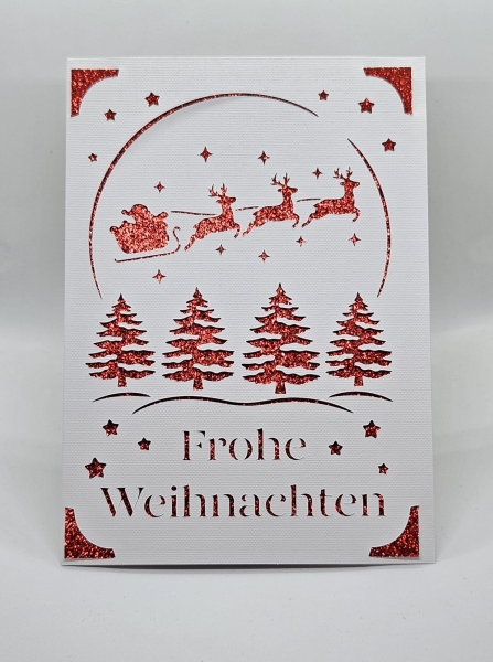 Vorderansicht einer handgefertigten Weihnachtskarte in Weiß mit glitzerndem roten Hintergrund. Filigranes Design zeigt Weihnachtsbäume, Sterne und den Schlitten des Weihnachtsmanns, gezogen von drei Rentieren. Text 'Frohe Weihnachten' ist kunstvoll ausges