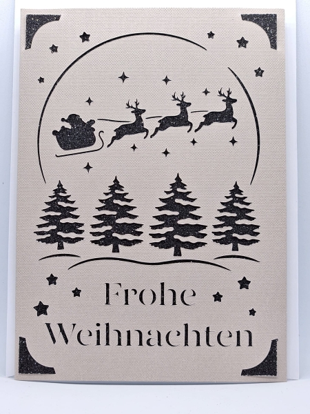 Handgefertigte Weihnachtskarte in Grau mit schwarzem Glitzerhintergrund. Filigranes Design mit dem Schlitten des Weihnachtsmanns, gezogen von drei Rentieren, umgeben von Sternen und Weihnachtsbäumen. Schriftzug 'Frohe Weihnachten' kunstvoll ausgeschnitten