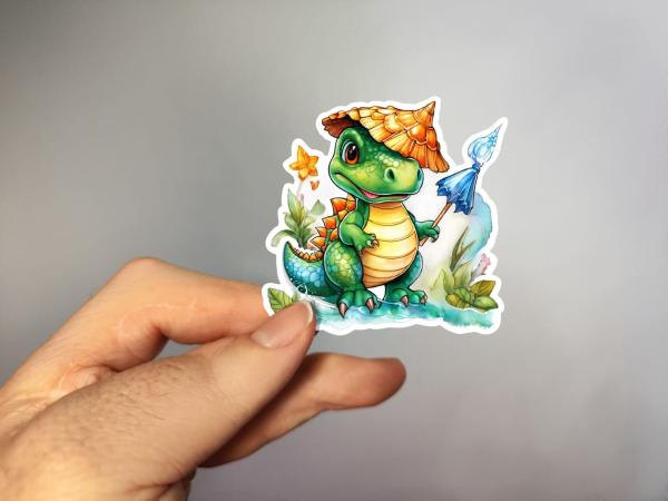 Niedlicher grüner Dinosaurier mit einem Strohhut und einem blauen Netz, umgeben von Blumen und Pflanzen. Der Dinosaurier hält das Netz in der Hand und steht auf einer Wiese.
