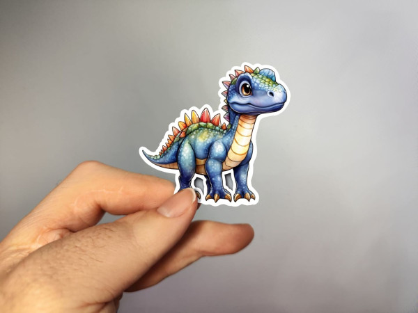 Kleiner blauer Dinosaurier mit bunten Rückenschuppen und großem Kopf. Der Dinosaurier hat einen freundlichen Ausdruck und steht gerade auf seinen vier Beinen.