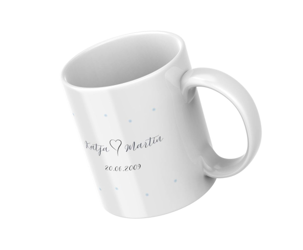 Weiße Keramiktasse mit Namen Katja und Martin und Datum 20.06.2009, schräg liegend dargestellt.