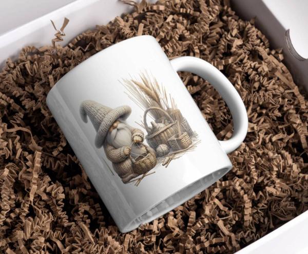 Weiße Tasse mit einem Motiv eines freundlichen Gnoms in einer großen gestrickten Mütze. Der Gnom hält einen Korb in den Händen und ist umgeben von weiteren Körben sowie Weizenhalmen. Perfekt für Liebhaber von ländlichem und rustikalem Design.