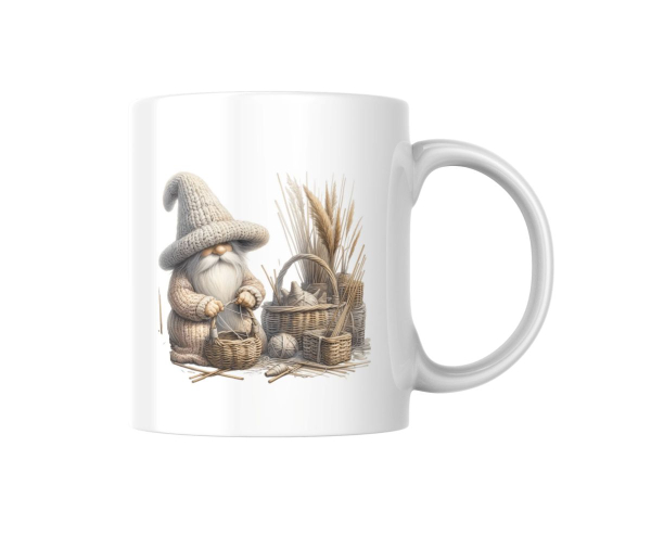 Weiße Tasse mit einer Illustration eines kleinen, strickenden Wichtels in einem großen Strickhut, der neben Körben mit Garn und Weizenbündeln sitzt. Ein gemütliches Design, das an das ländliche Leben erinnert.