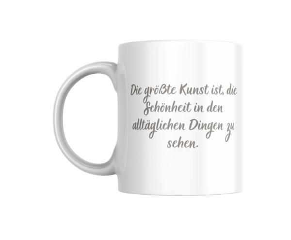 Weiße Tasse mit der Aufschrift 'Die größte Kunst ist, die Schönheit in den alltäglichen Dingen zu sehen.' Ein inspirierender Spruch in eleganter Schrift, ideal für kreative Menschen und Kunstliebhaber.