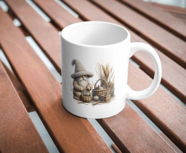Weiße Tasse mit einem niedlichen Motiv eines kleinen, handwerkenden Wichtels in einem großen Strickhut, umgeben von Körben und Weizenbündeln. Das Bild zeigt eine warme, rustikale Szene, die ländliche Handwerkskunst widerspiegelt.