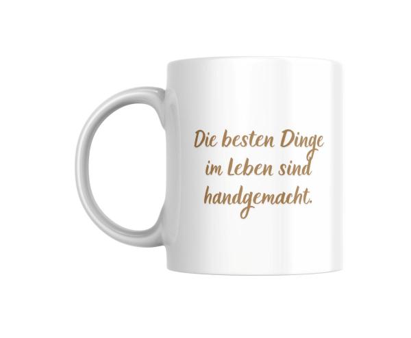 Weißer Keramikbecher mit der Aufschrift ‚Die besten Dinge im Leben sind handgemacht‘ in einer stilvollen, geschwungenen Schrift. Ein ideales Geschenk für alle, die handgefertigte Produkte und Kreativität schätzen.