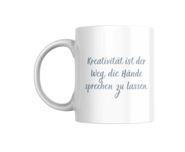 Weißer Keramikbecher mit der Aufschrift ‚Kreativität ist der Weg, die Hände sprechen zu lassen‘ in einer eleganten, geschwungenen Schrift. Perfektes Geschenk für kreative Köpfe und Handarbeitsliebhaber.