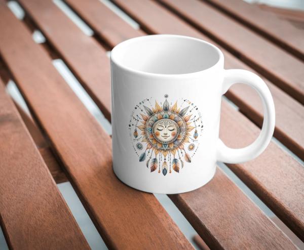 Weißer Keramikbecher mit einem Boho-Sonnenmotiv, das ein friedliches Gesicht umgeben von Blättern, Federn und dekorativen Elementen zeigt. Der Becher steht auf einem Holztisch und ist ein ideales Geschenk für Liebhaber spiritueller und boho-inspirierter K