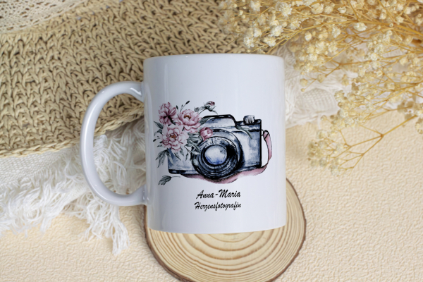 Weiße personalisierte Tasse mit Aquarell-Kamera und rosa Blumen, darunter der Name „Anna-Maria“ und der Schriftzug „Herzensfotografin“. Ideal als Geschenk für Fotografen oder Fotografinnen mit Herz und Stil.
