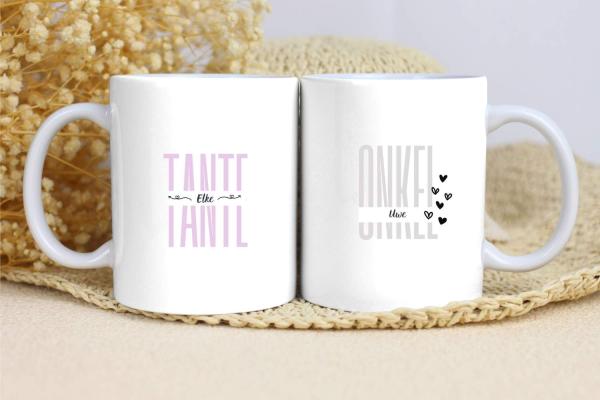 Zwei weiße Tassen mit schlichten Designs. Die linke Tasse trägt den Text „TANTE“ in einem sanften Lila, mit dem Namen „Elke“ darunter und dekorativen Linien auf beiden Seiten. Die rechte Tasse zeigt den Text „ONKEL“ in einem dezenten Grau, mit dem Namen „