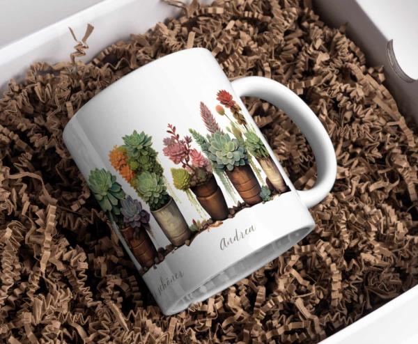Weiße Tasse mit Illustrationen von verschiedenen Sukkulenten in Töpfen und dem Namen ‚Andrea‘. Ein schönes und personalisierbares Geschenk für Pflanzenliebhaber.